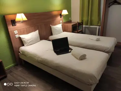 Un ou plusieurs lits dans un hébergement de l'établissement Glisy Hôtel