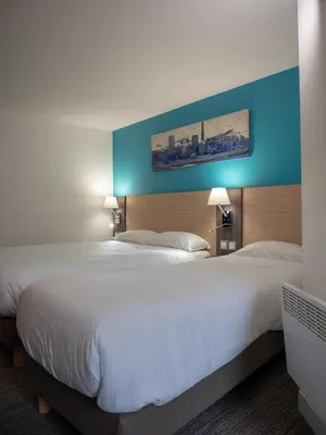 Un ou plusieurs lits dans un hébergement de l'établissement Contact Hotel Bleu France Eragny Cergy
